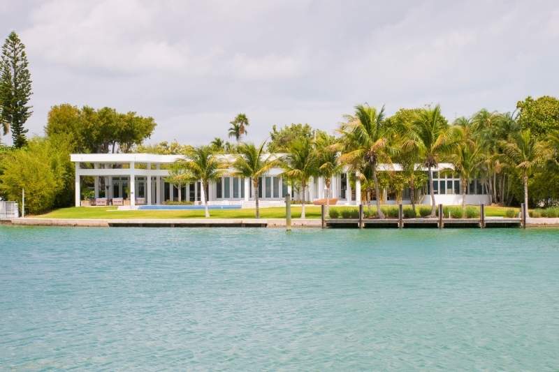 View of the river and the back of the Miami Beach Glass House with palm trees